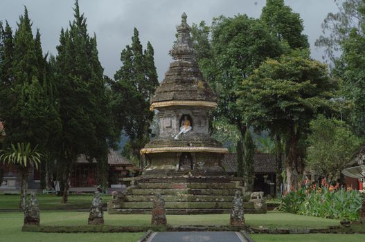 A serene ancient Balinese temple with a prominent Buddha statue in a lush garden setting, symbolizing spirituality and peace.