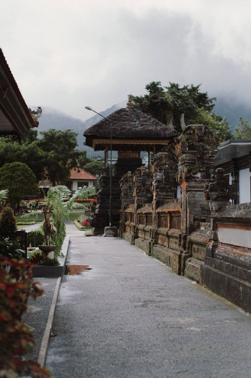 Free Serene outdoor temple path in Bali, surrounded by lush greenery and traditional architecture. Stock Photo