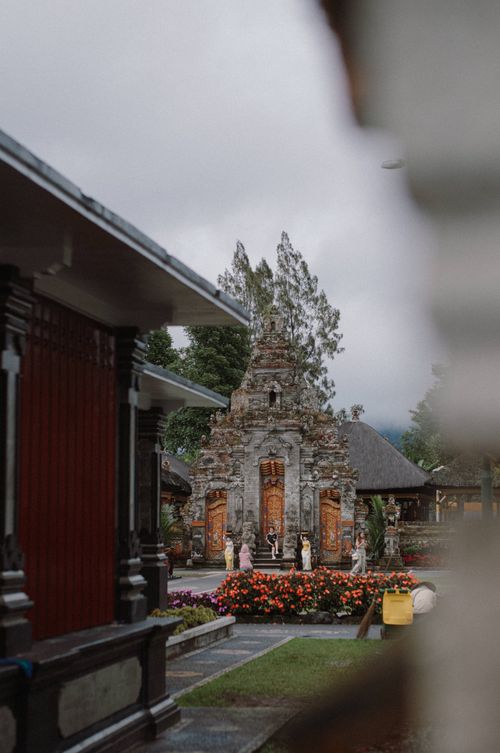Free Beautiful view of a traditional Indonesian temple surrounded by vibrant flowers and greenery. Stock Photo