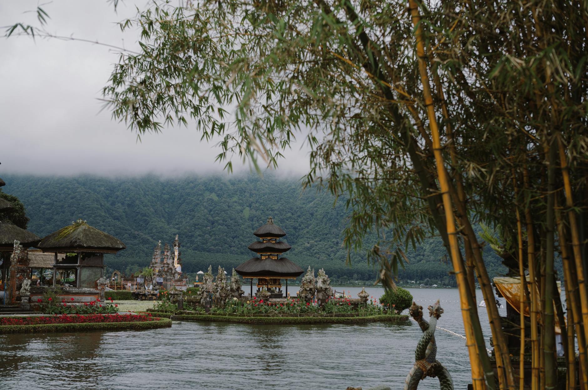 A tranquil scene of the Ulun Danu Beratan Temple in Bali, surrounded by lush greenery and misty mountains.