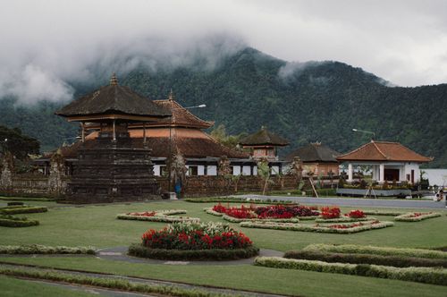 Free A peaceful Balinese temple surrounded by vibrant gardens and lush mountains, offering a glimpse into traditional architecture. Stock Photo