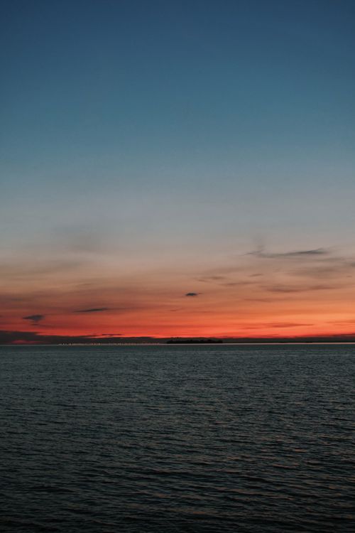 Free Stunning sunset over a calm ocean, capturing vibrant hues and peaceful reflections. Stock Photo
