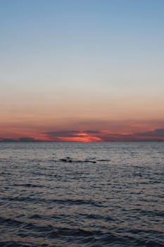 Serene ocean sunset with vibrant colors reflecting on calm waters, perfect for travel inspiration.