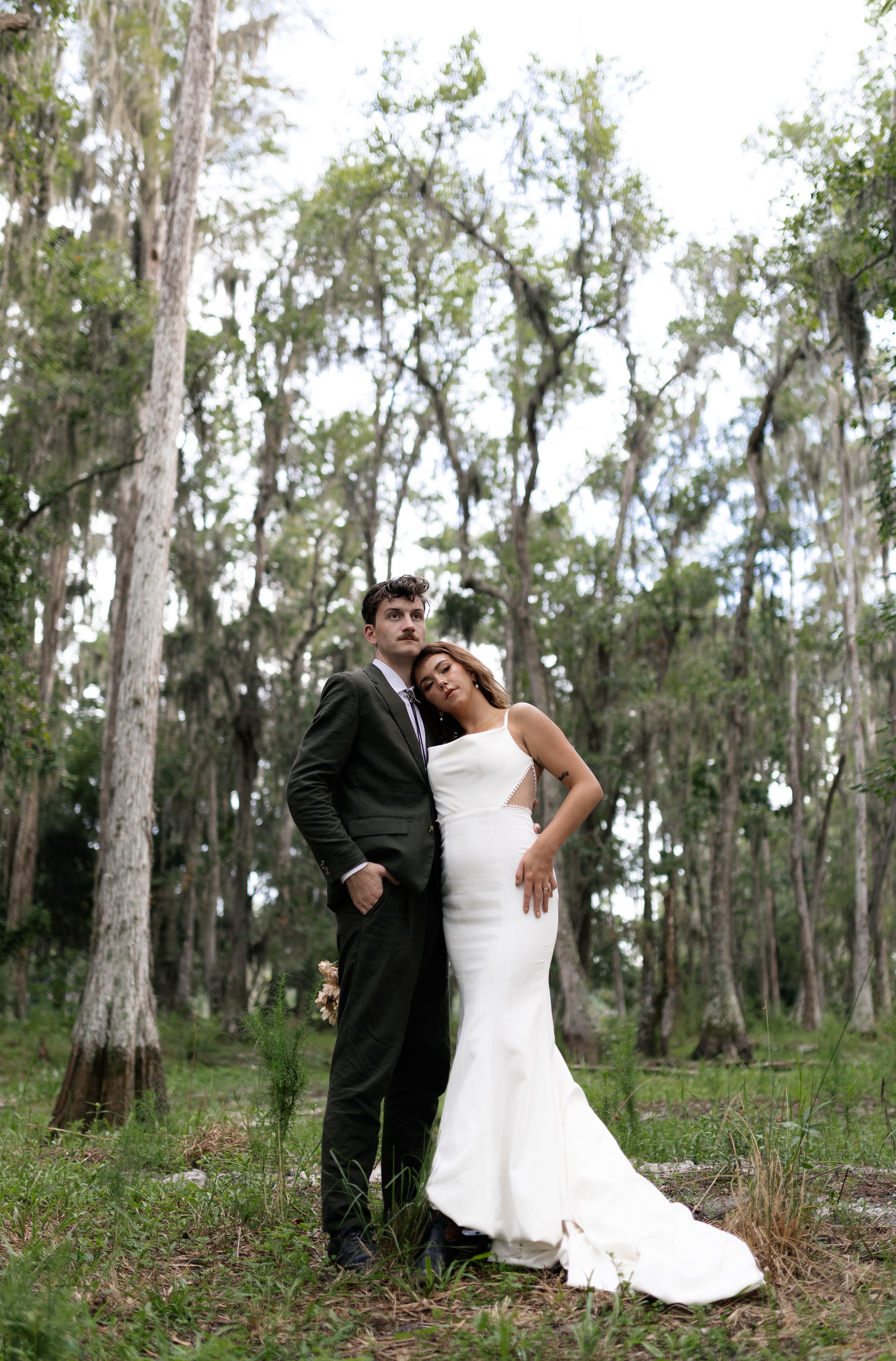 A bride and groom pose for a photo in the woods · Free Stock Photo