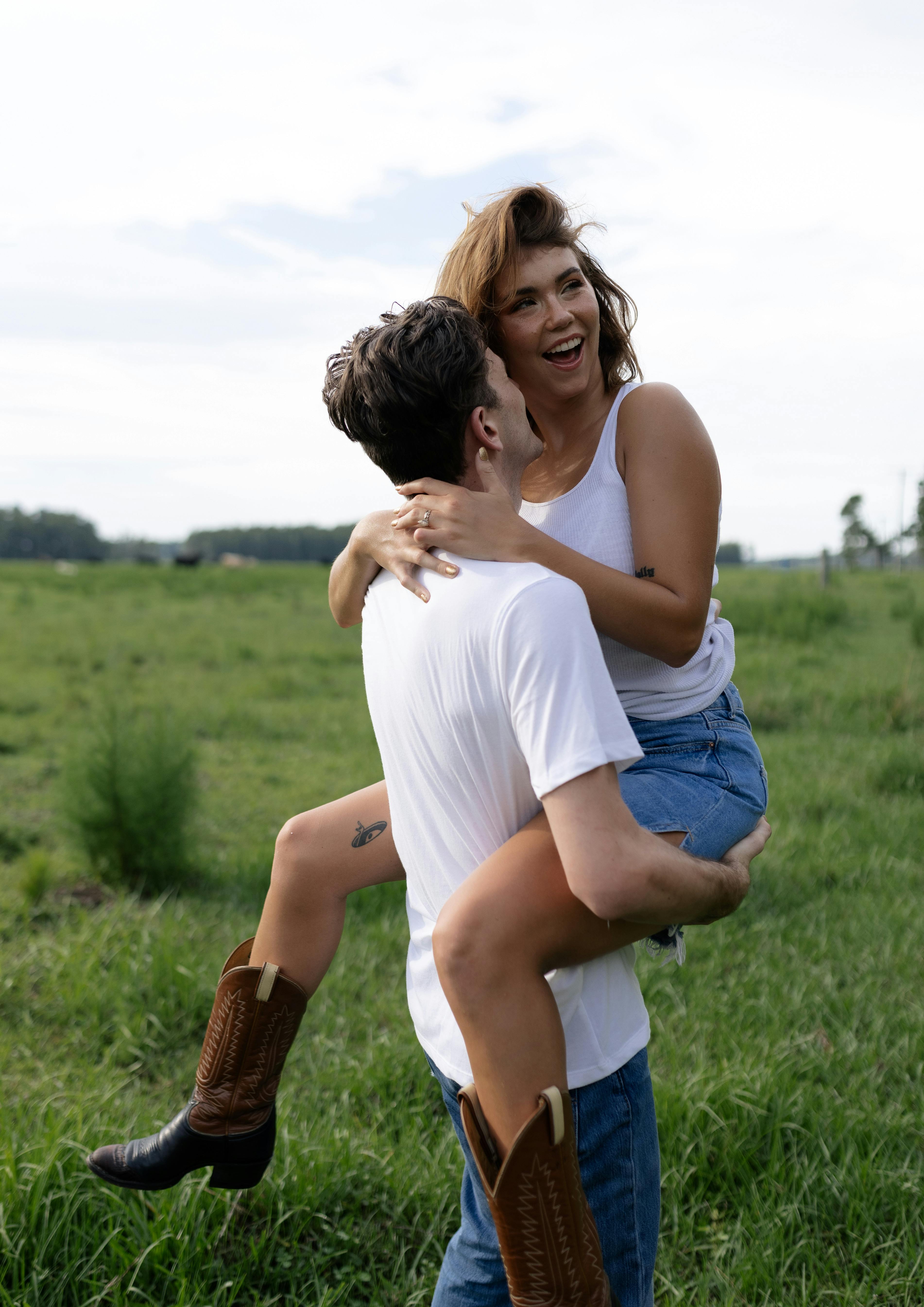 a man is carrying a woman in the grass