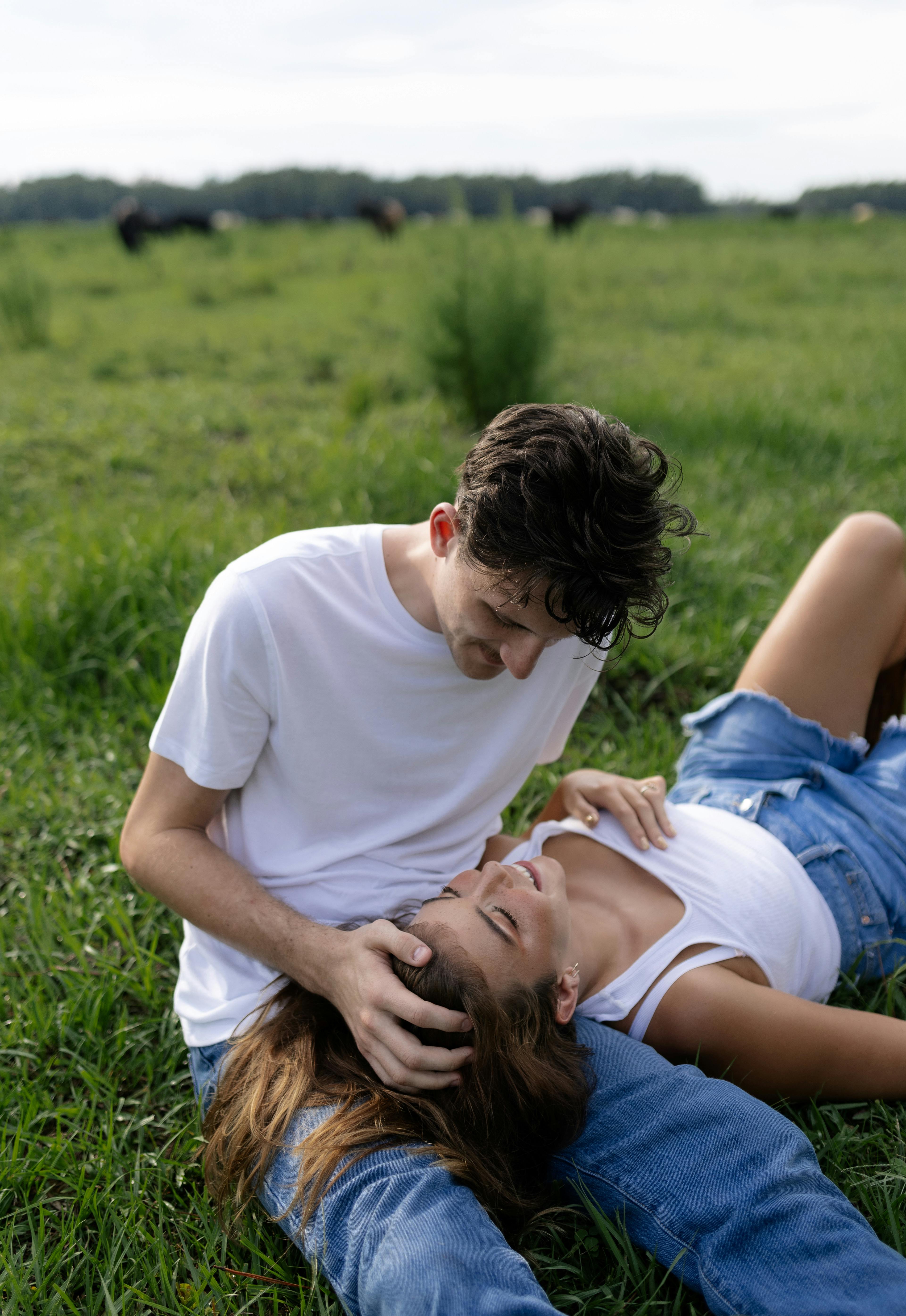 a man and woman laying on the grass in a field