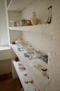 White rustic shelves displaying a collection of vintage crockery in a cozy kitchen setting.