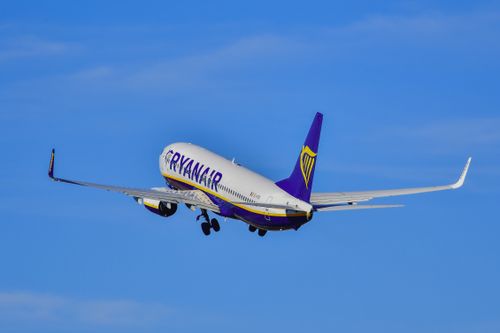 Free A Ryanair airplane ascends into a cloudless sky, showcasing aviation and travel excitement. Stock Photo