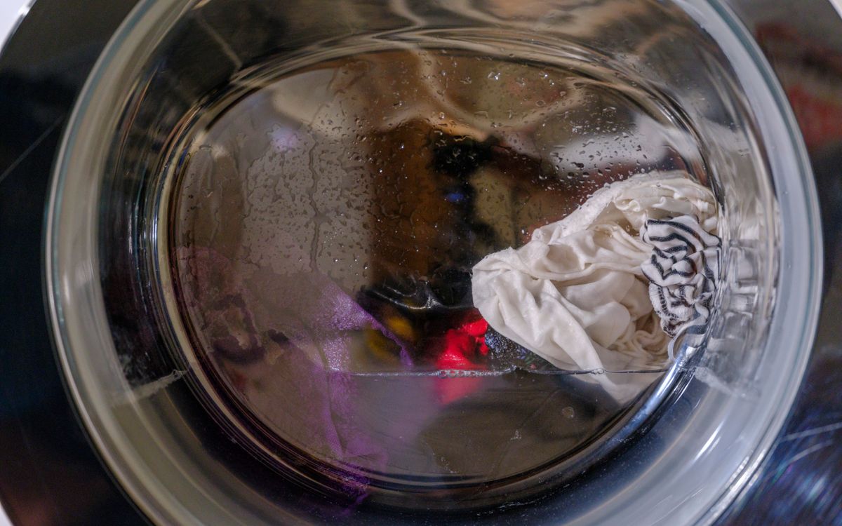A clear view of wet clothes spinning inside a front-loading washing machine.