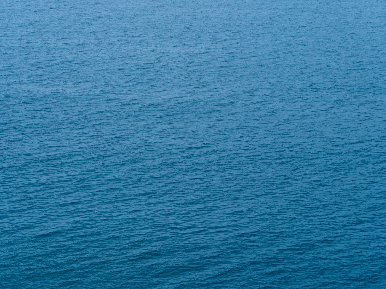 a serene view of the deep blue ocean surface with gentle waves creatin