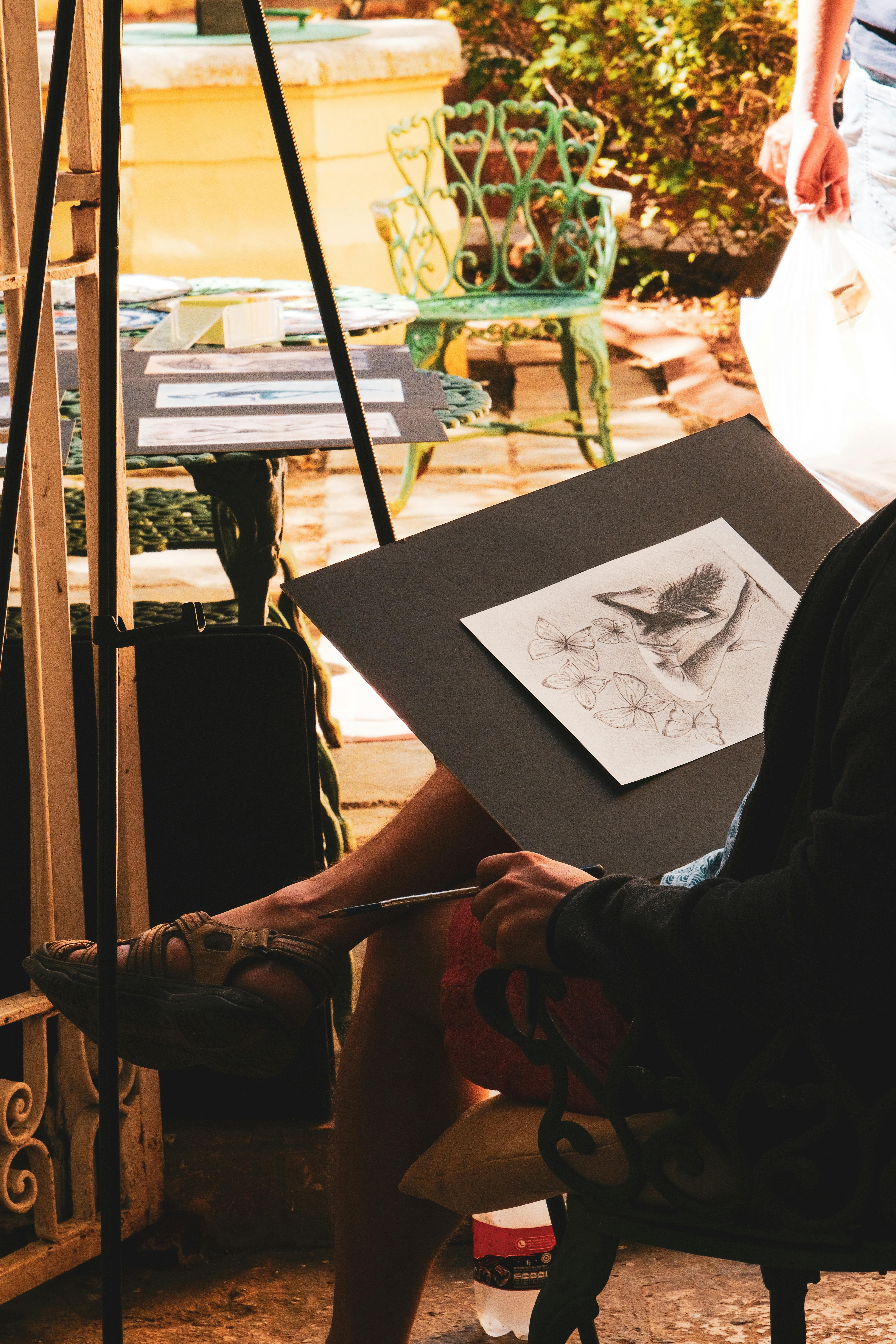 a woman sitting on a chair with a drawing on the easel