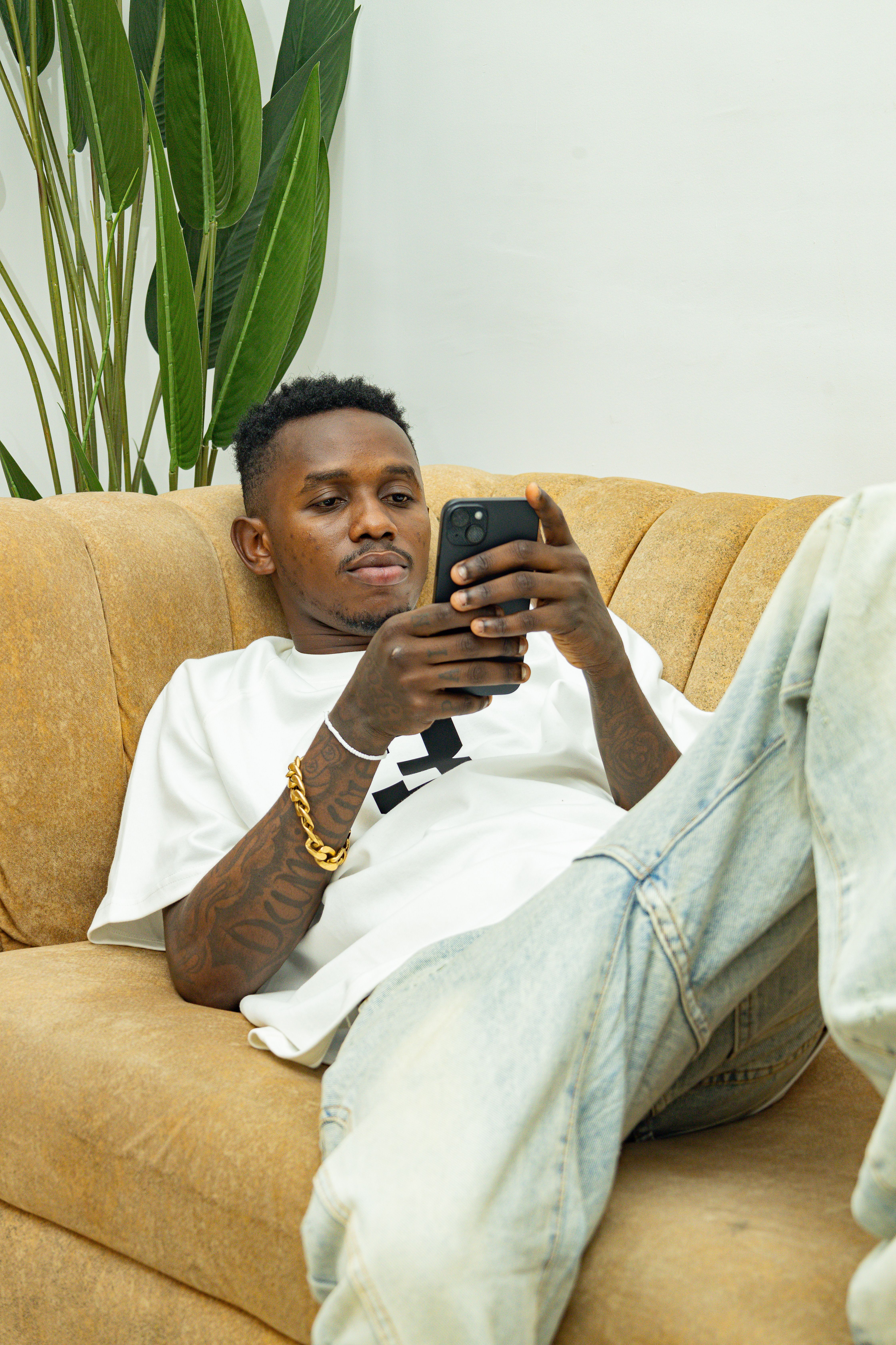 A man lounging on a sofa, browsing his smartphone in a relaxed setting indoors.