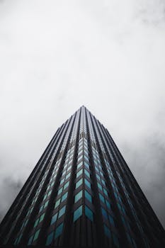 Vertical shot of a towering modern skyscraper reaching into a cloudy sky, emphasizing architectural height.