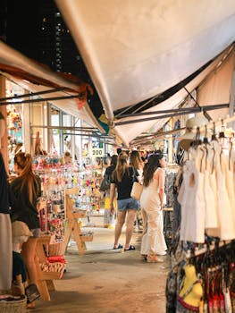 Explore a bustling night market in Bangkok with diverse shops and engaged shoppers.