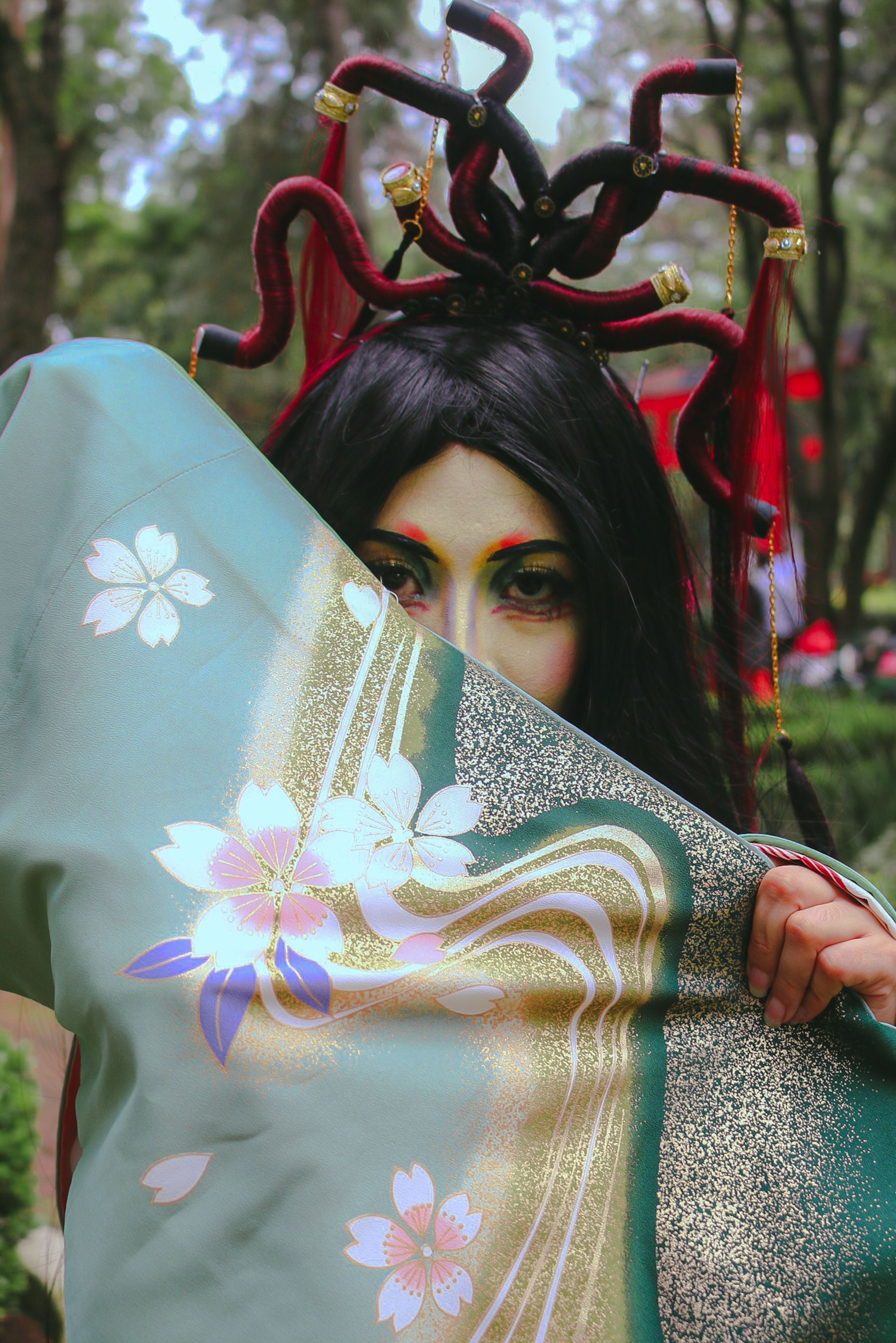 Woman in traditional attire with floral design, featuring striking headpiece, outdoors.