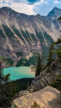 Breathtaking view of turquoise mountain lake surrounded by rocky cliffs and pine trees.