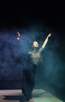 Ballet dancer gracefully performs amidst dramatic smoke, showcasing elegance and artistry.