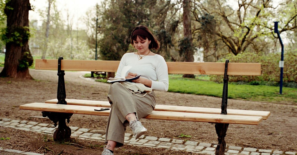 Woman Sitting on a Park Bench and Taking Notes · Free Stock Photo