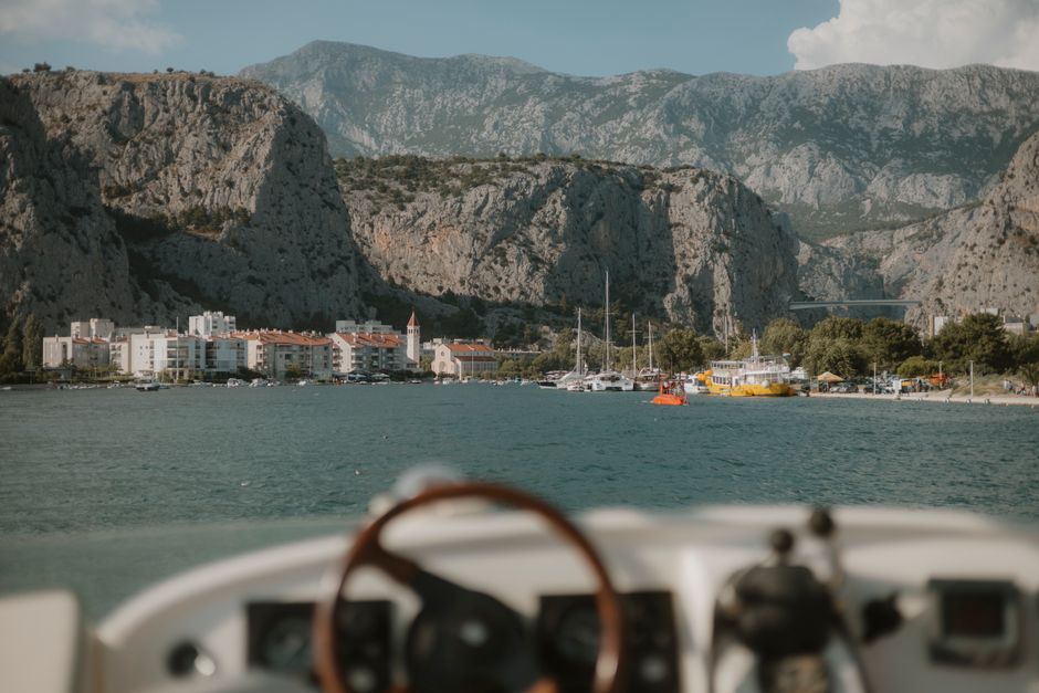 Discover the picturesque Omiš harbor surrounded by majestic cliffs and blue waters, perfect for a summer getaway.