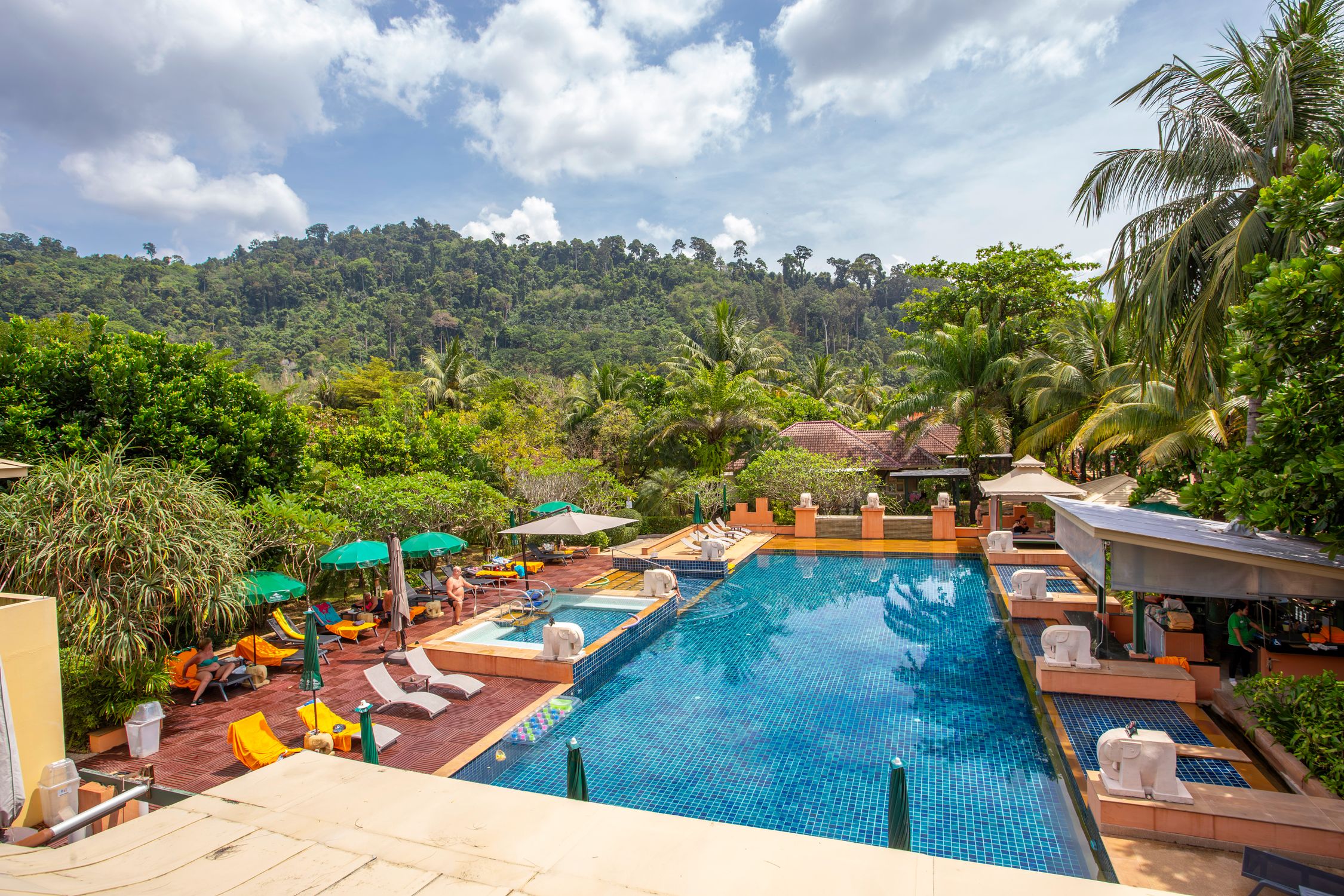 Relax by a serene pool at a luxury resort surrounded by tropical nature.