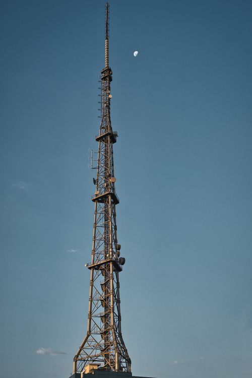 Free Tall steel telecommunication tower with moon in the sky, São Paulo. Stock Photo