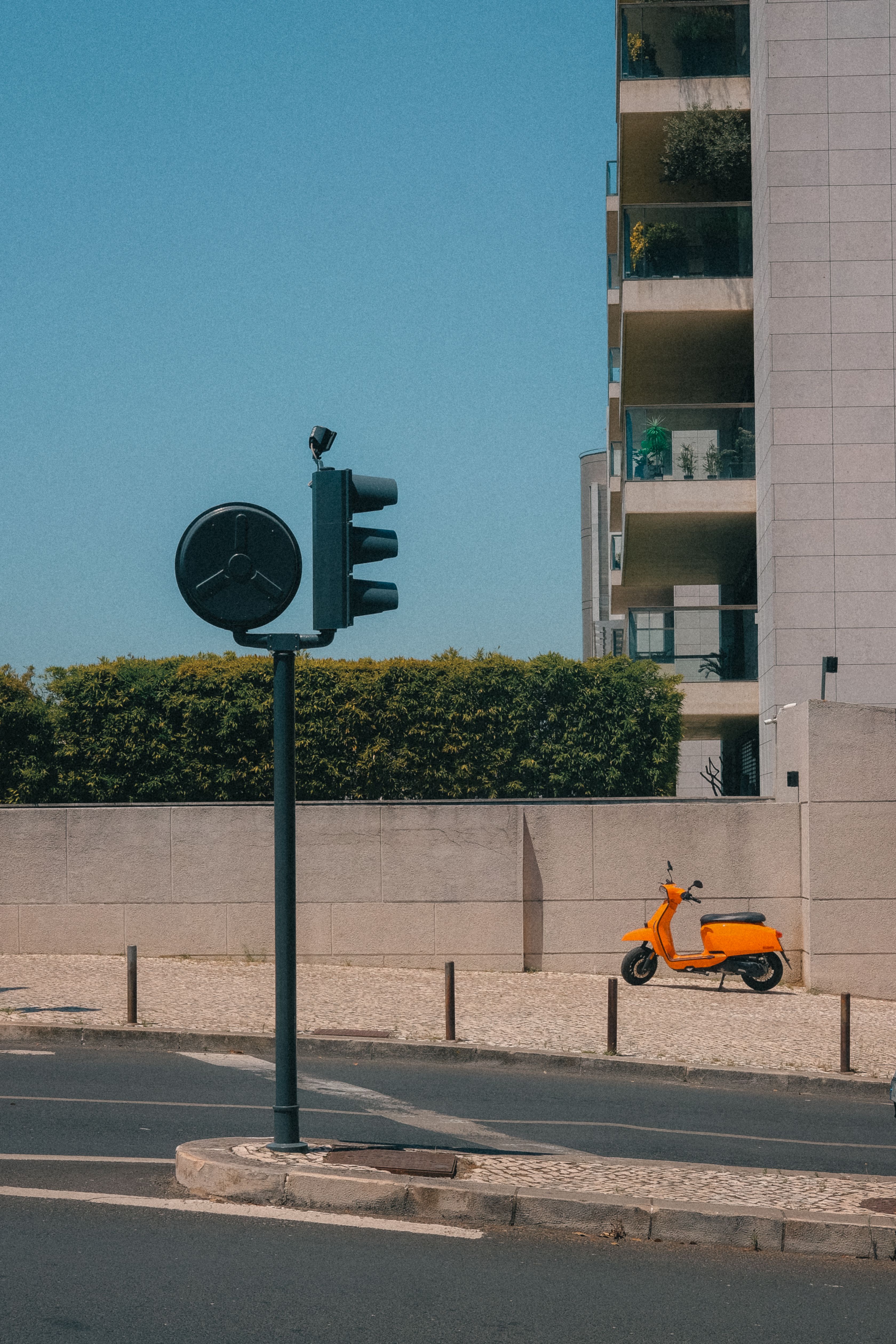 Vibrant city street scene featuring an orange scooter and traffic signal in Lisbon.