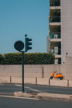 Vibrant city street scene featuring an orange scooter and traffic signal in Lisbon.