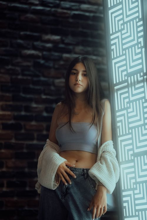 Free Stylish young woman poses casually indoors with a modern aesthetic. Stock Photo