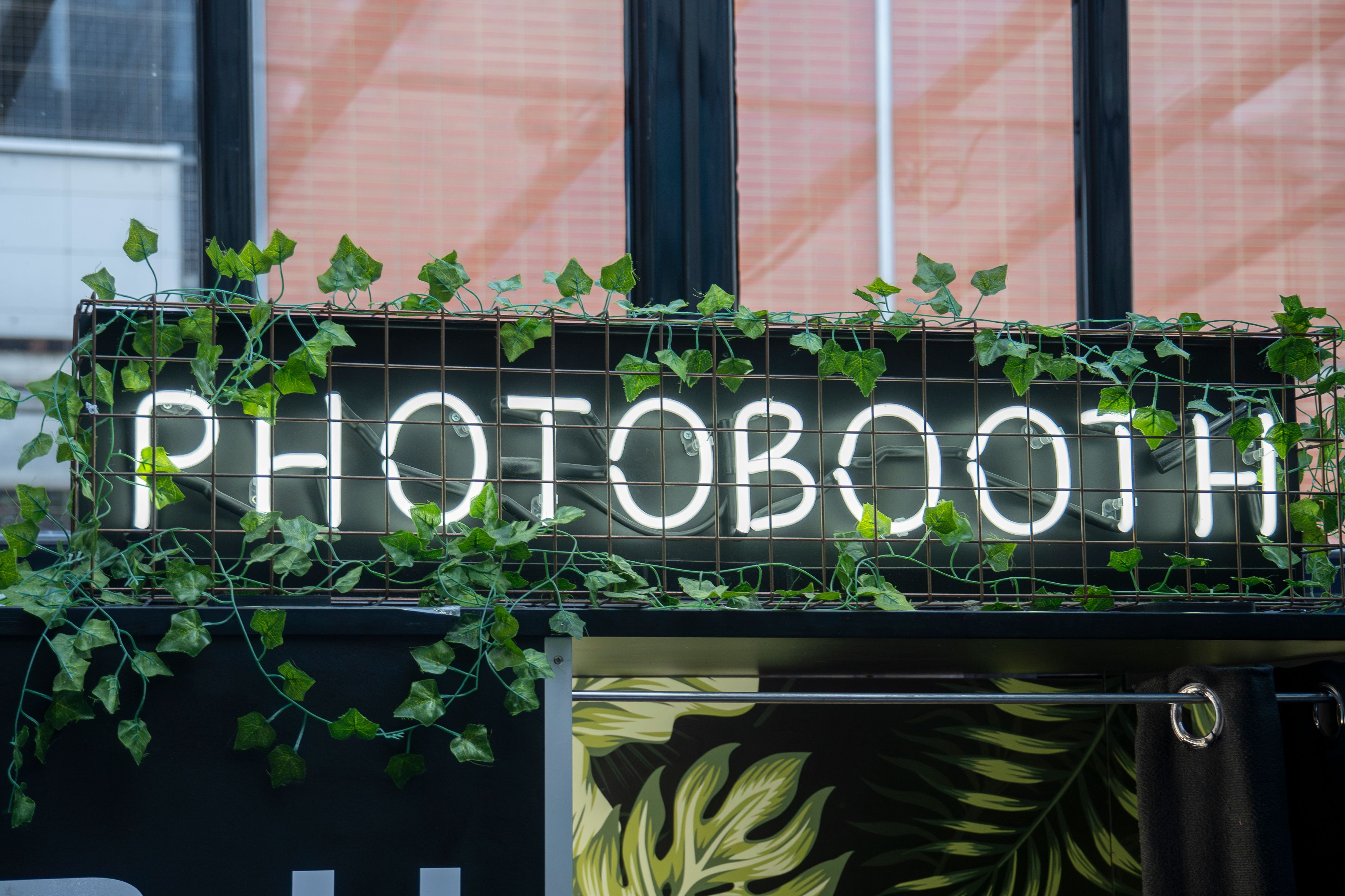 A neon photo booth sign glowing outside an event space