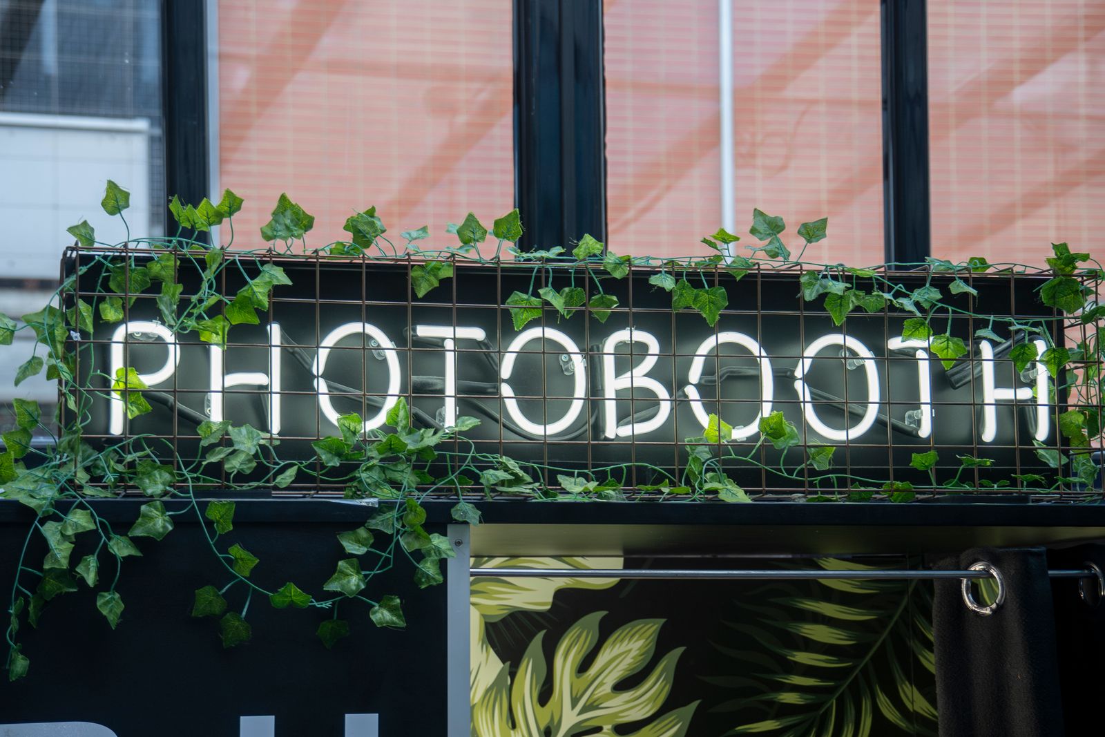 Neon PHOTOBOOTH sign wrapped in greenery