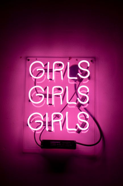Vibrant pink neon light with the word 'Girls' repeated three times, creating a bold and retro ambiance.