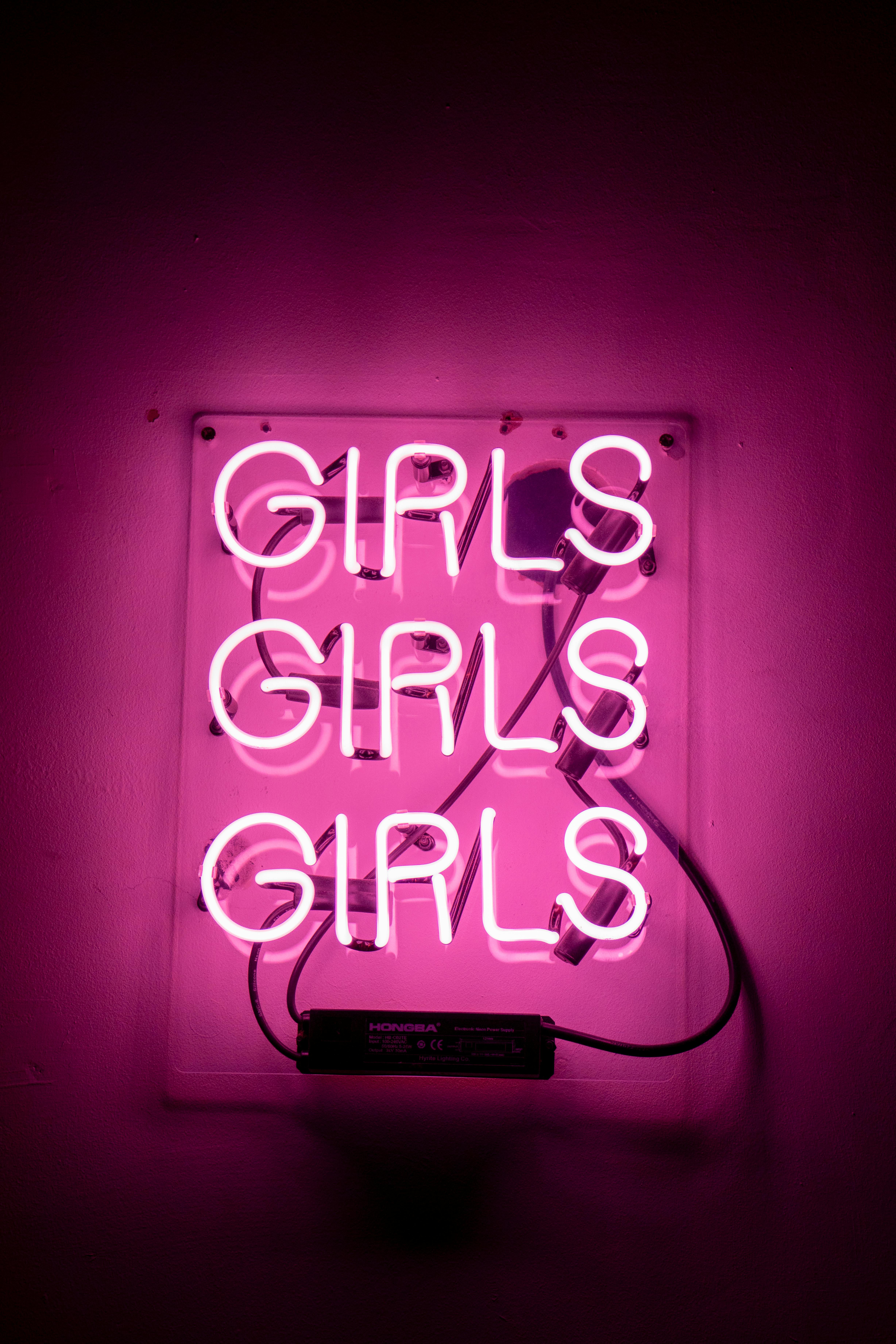 Free Vibrant pink neon light with the word 'Girls' repeated three times, creating a bold and retro ambiance. Stock Photo