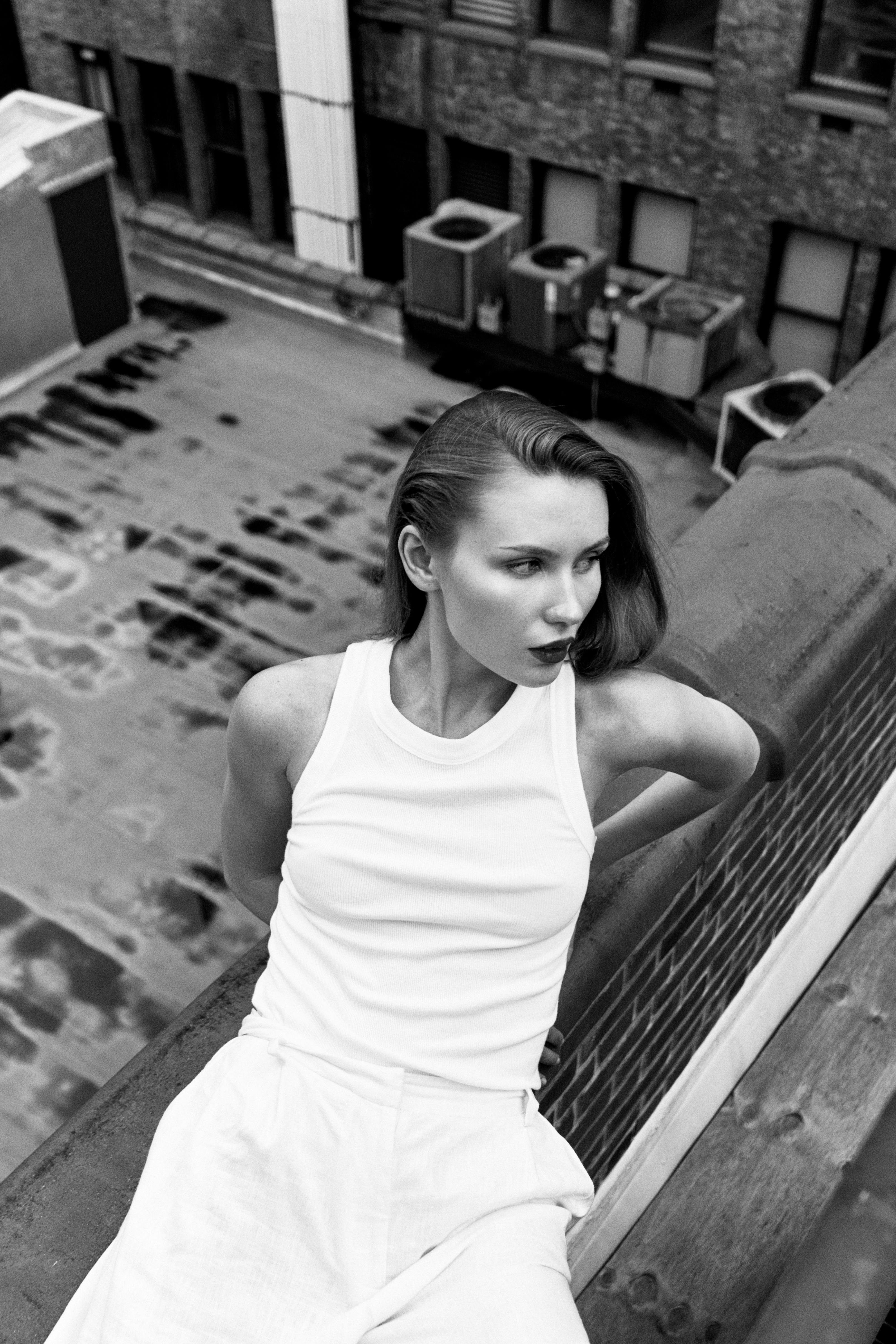 a woman in white sitting on a ledge