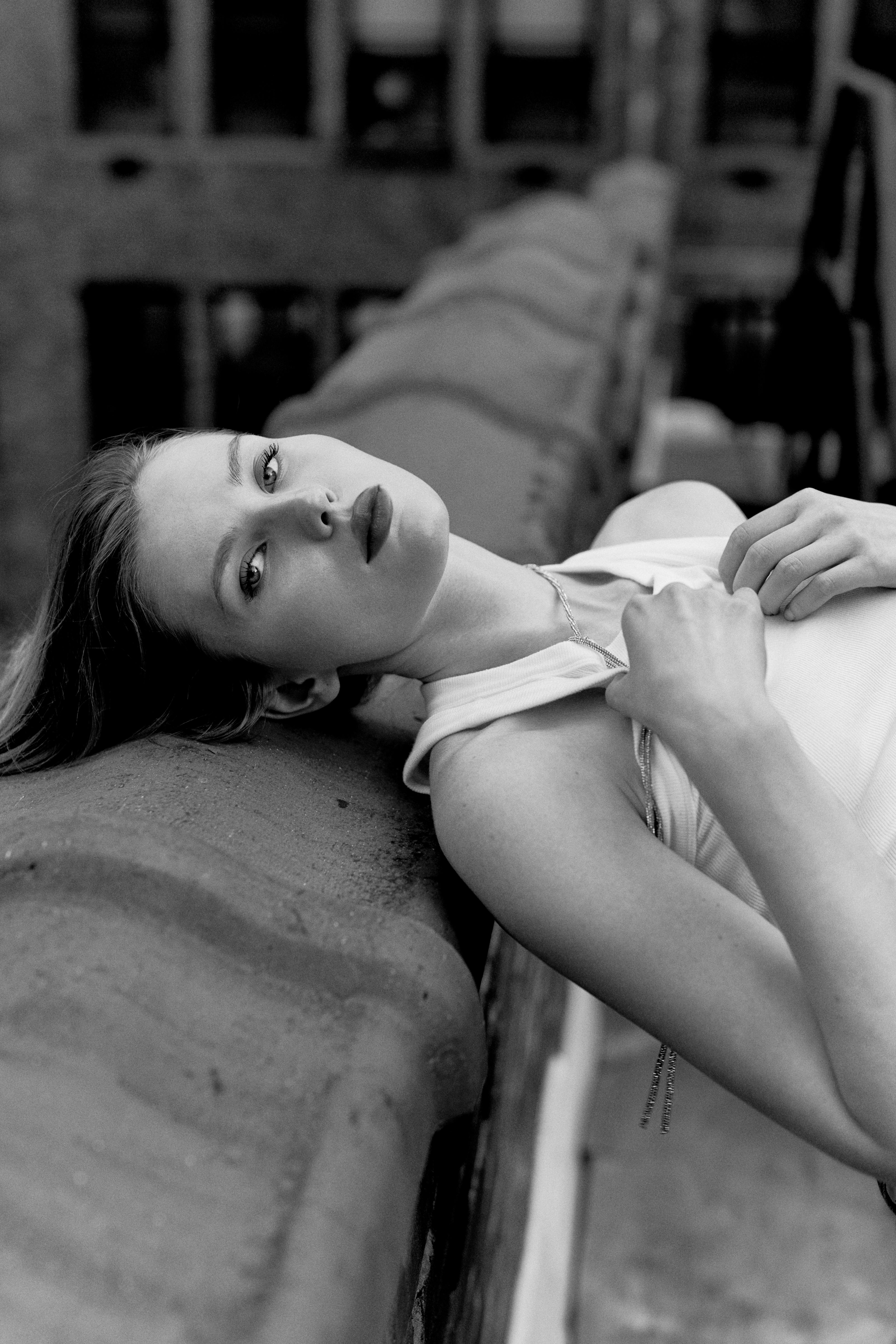 a woman laying on a ledge with her hands on her head