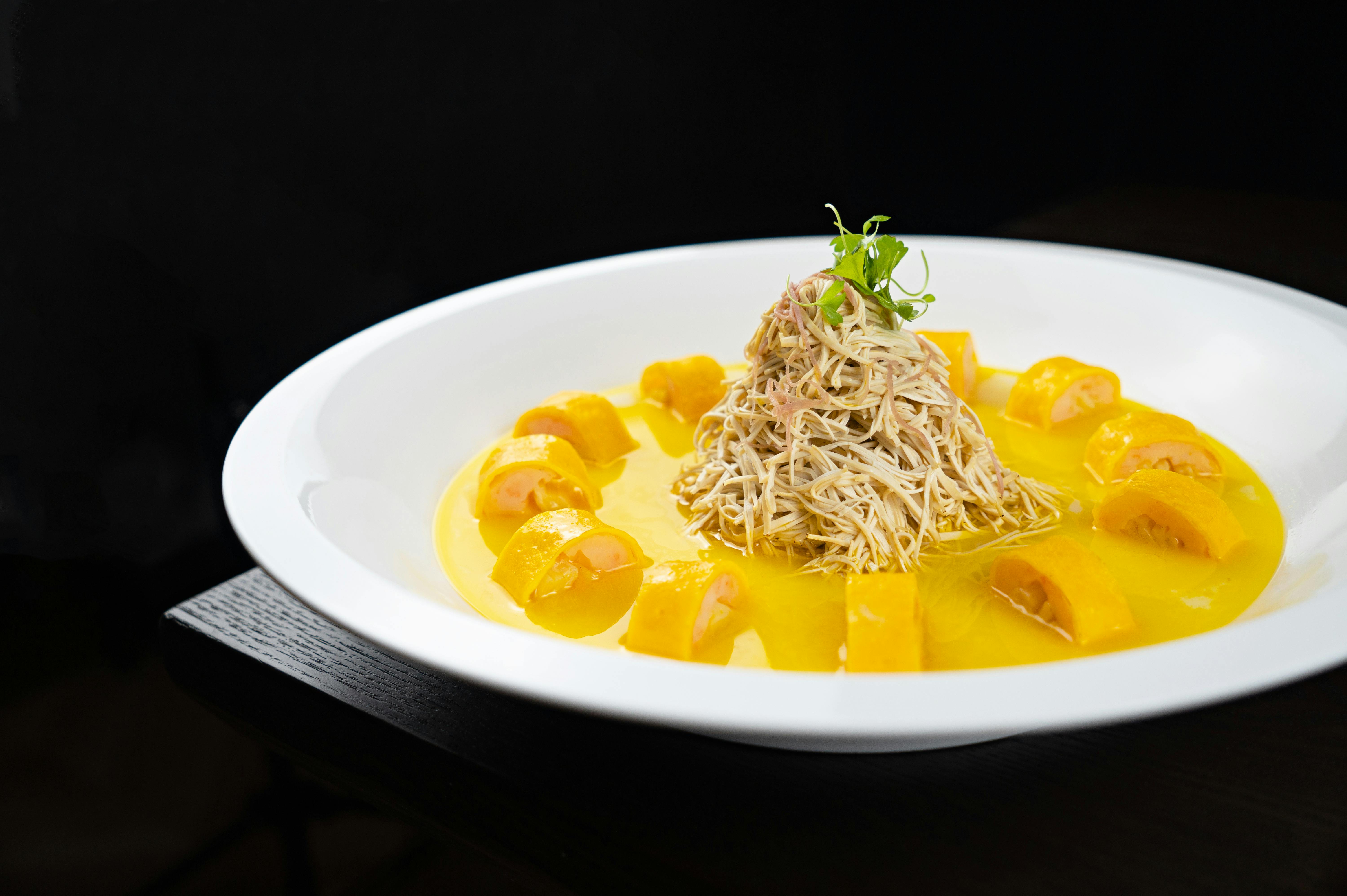 Exquisite plated dish featuring pasta with a creamy, vibrant yellow sauce.