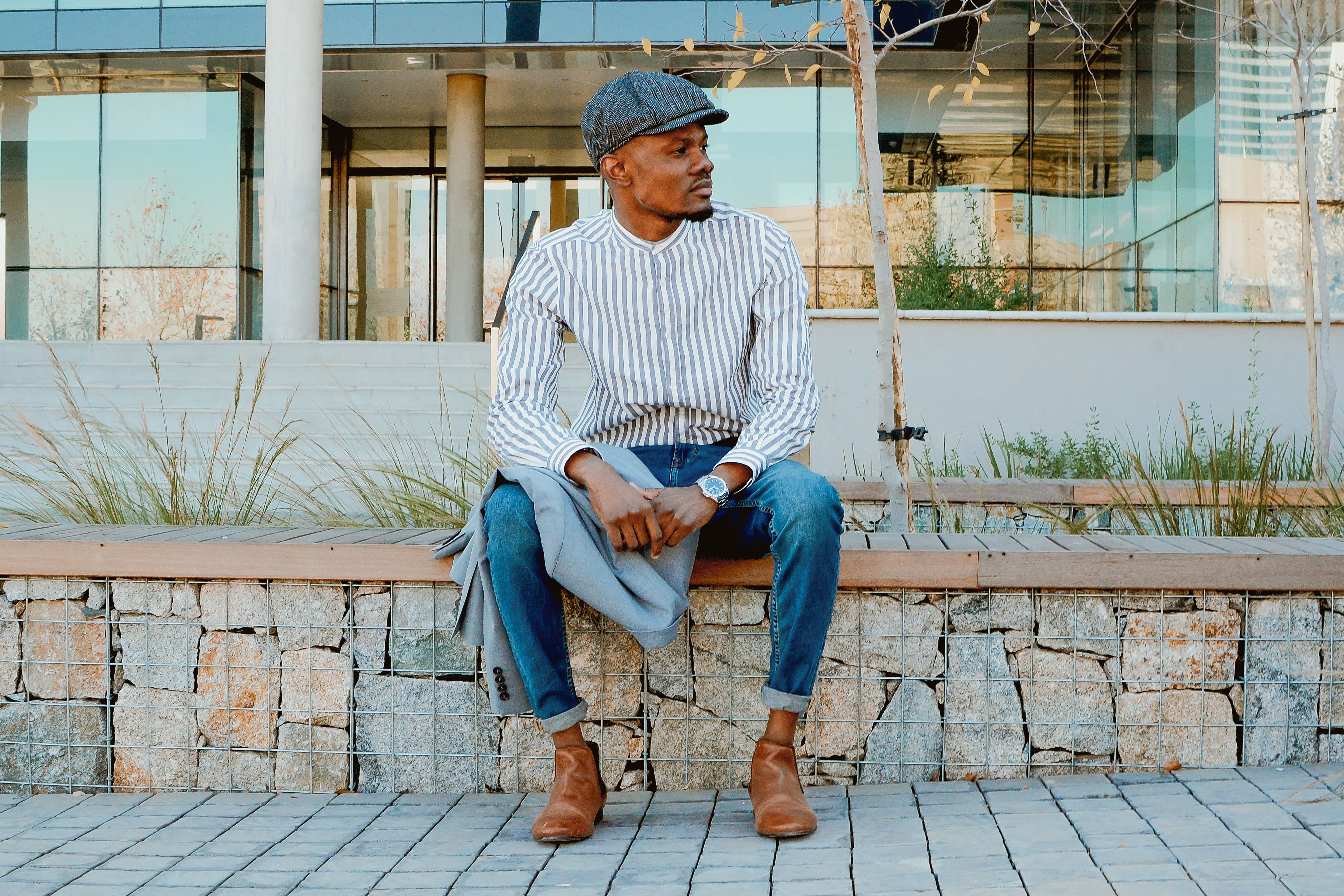 Well-dressed in Flat Cap Sitting on Stone Wall · Free Stock Photo