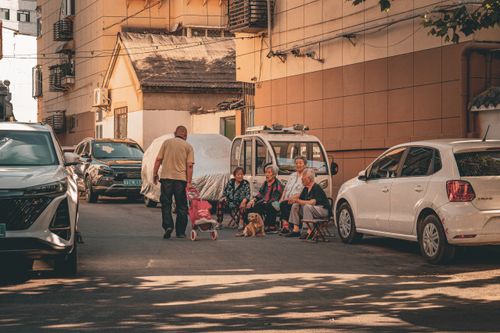 Free A group of senior adults and a man with a stroller in a busy urban street setting filled with cars. Stock Photo