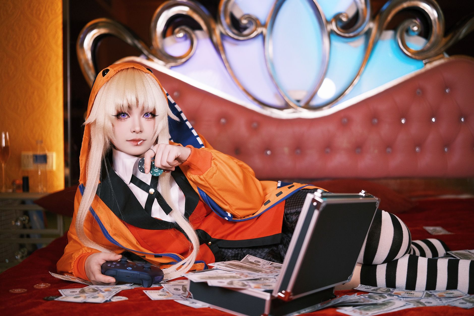 Cosplayer in vibrant outfit lounging on bed with game controller and cash, creating a playful scene.