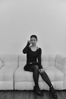 Black and white portrait of a woman sitting on a sofa, embodying modern elegance.