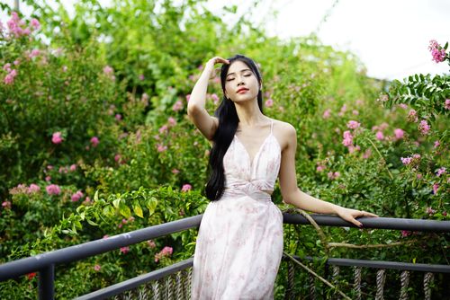 Free A young woman in a floral dress enjoys a serene moment outdoors amidst vibrant greenery. Stock Photo