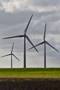 Wind turbines generating renewable energy on a grassy landscape under cloudy skies.
