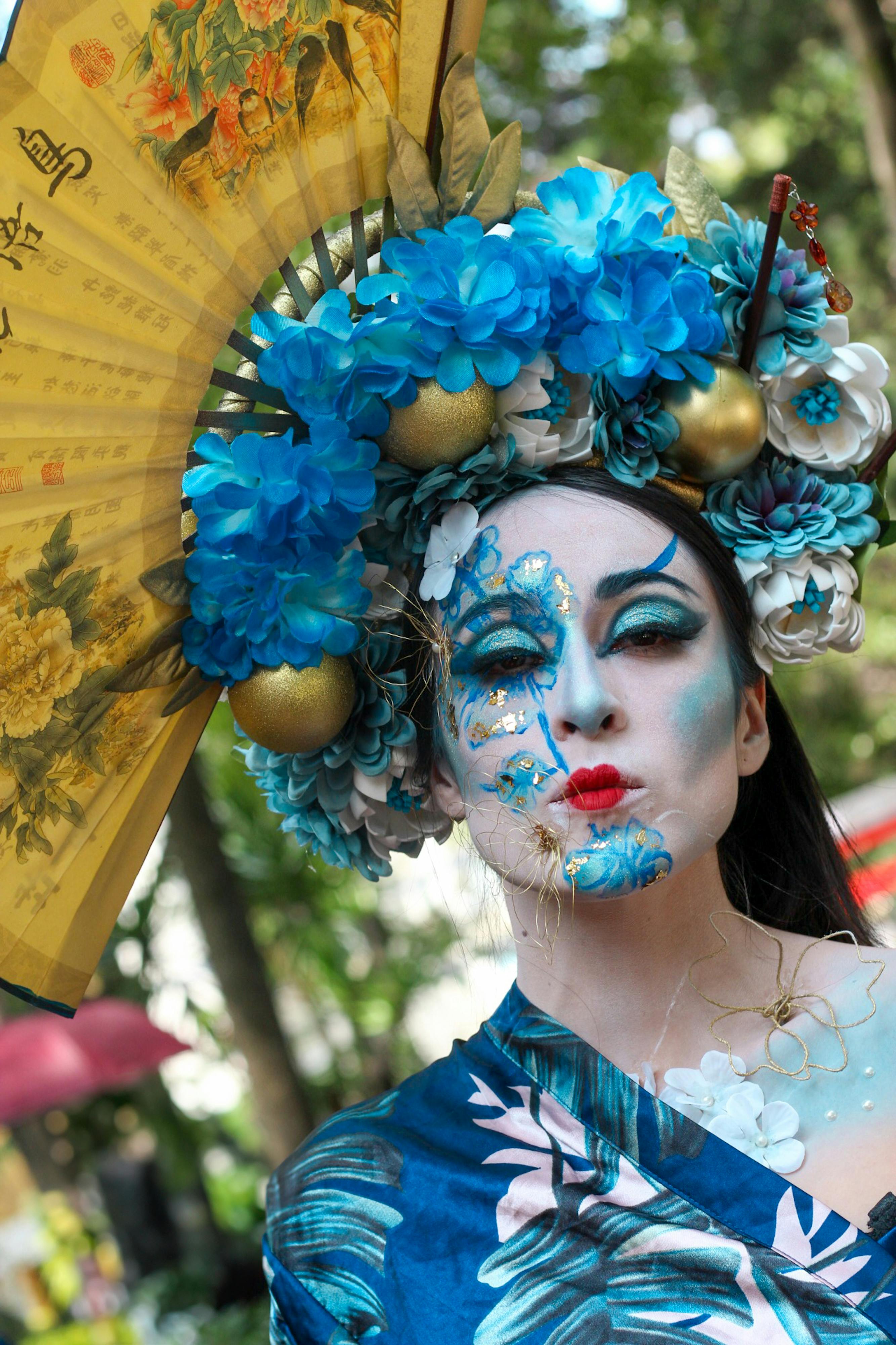 a woman with blue makeup and a fan