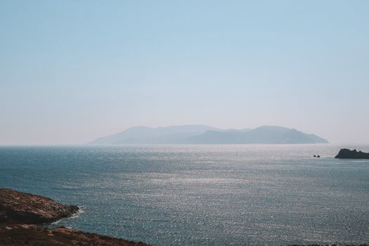 Peaceful view of the Aegean Sea with distant Greek islands under a clear sky.