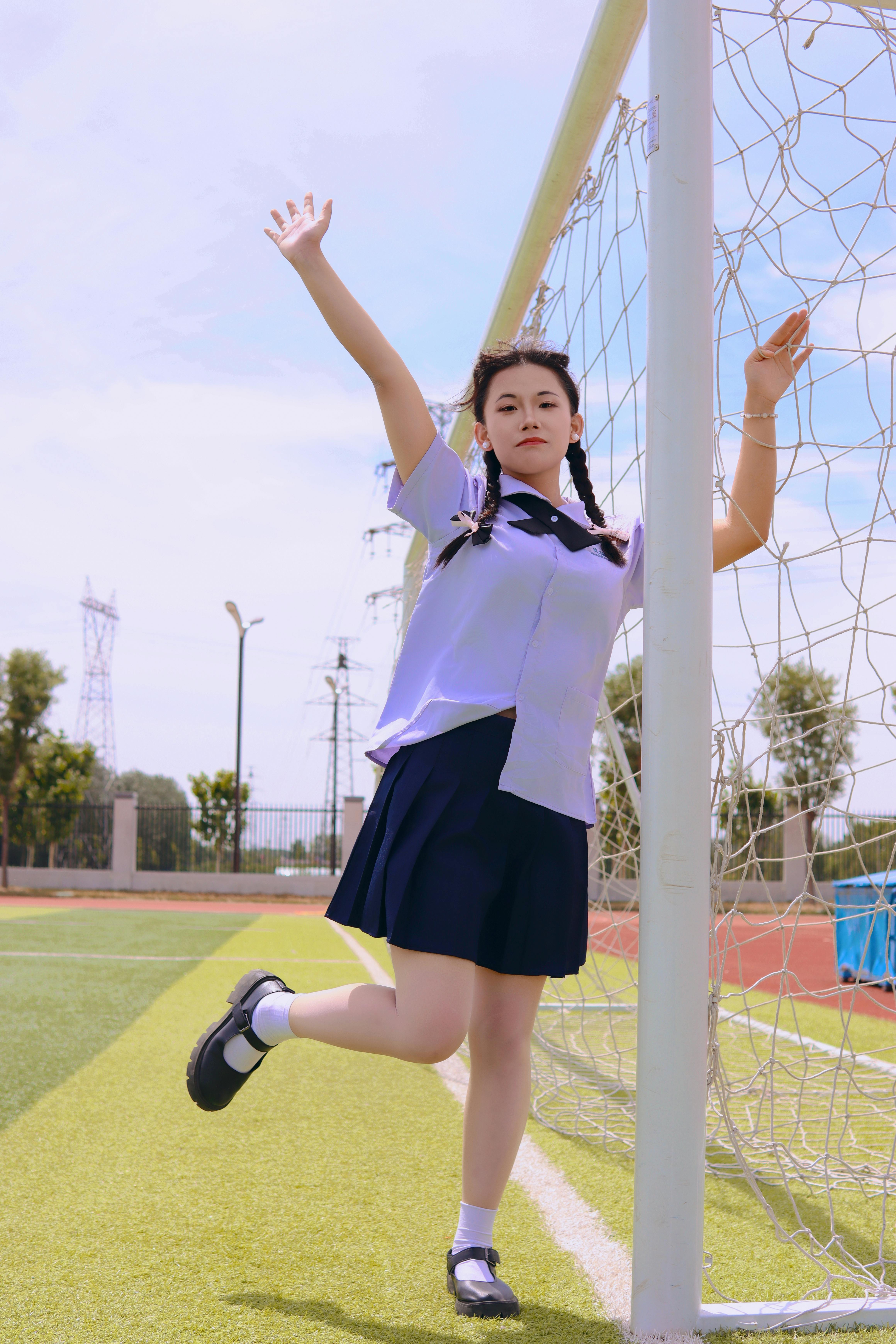 Young girl playfully standing by soccer goal on a sunny day, exuding fun and relaxation.