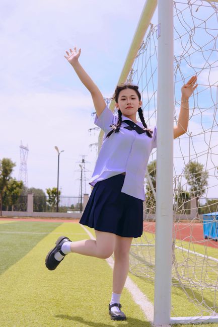 Young girl playfully standing by soccer goal on a sunny day, exuding fun and relaxation.