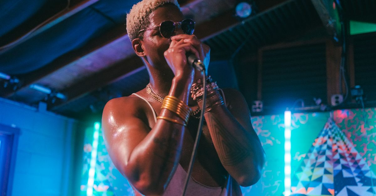 live hyperpop concert with crowd in colorful outfits and a performer with a microphone