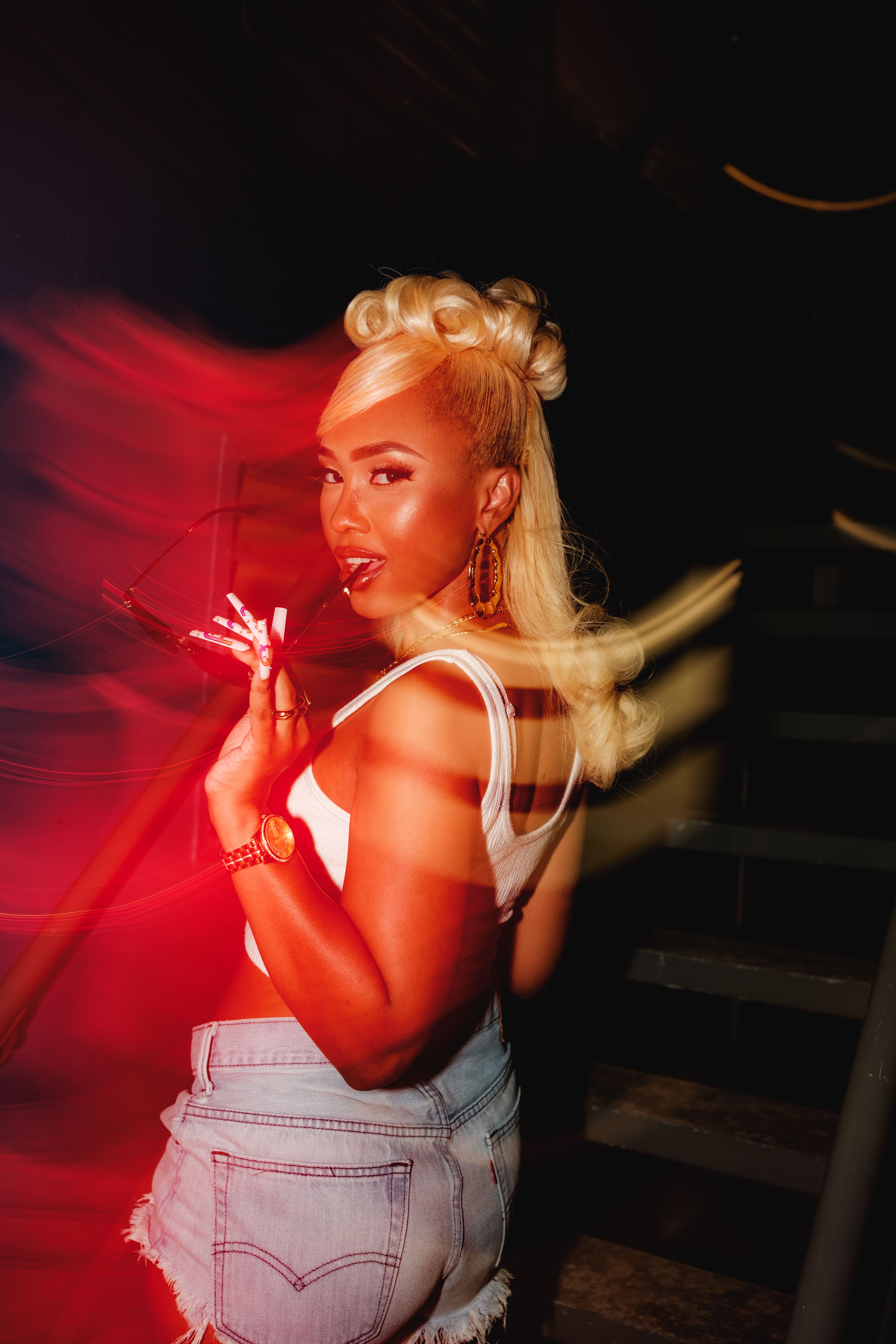 Stylish woman posing confidently in a vibrant, nightclub atmosphere.