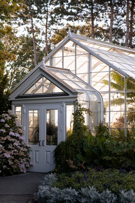 A beautiful greenhouse entrance in Seattle surrounded by lush greenery and flowers during daytime.