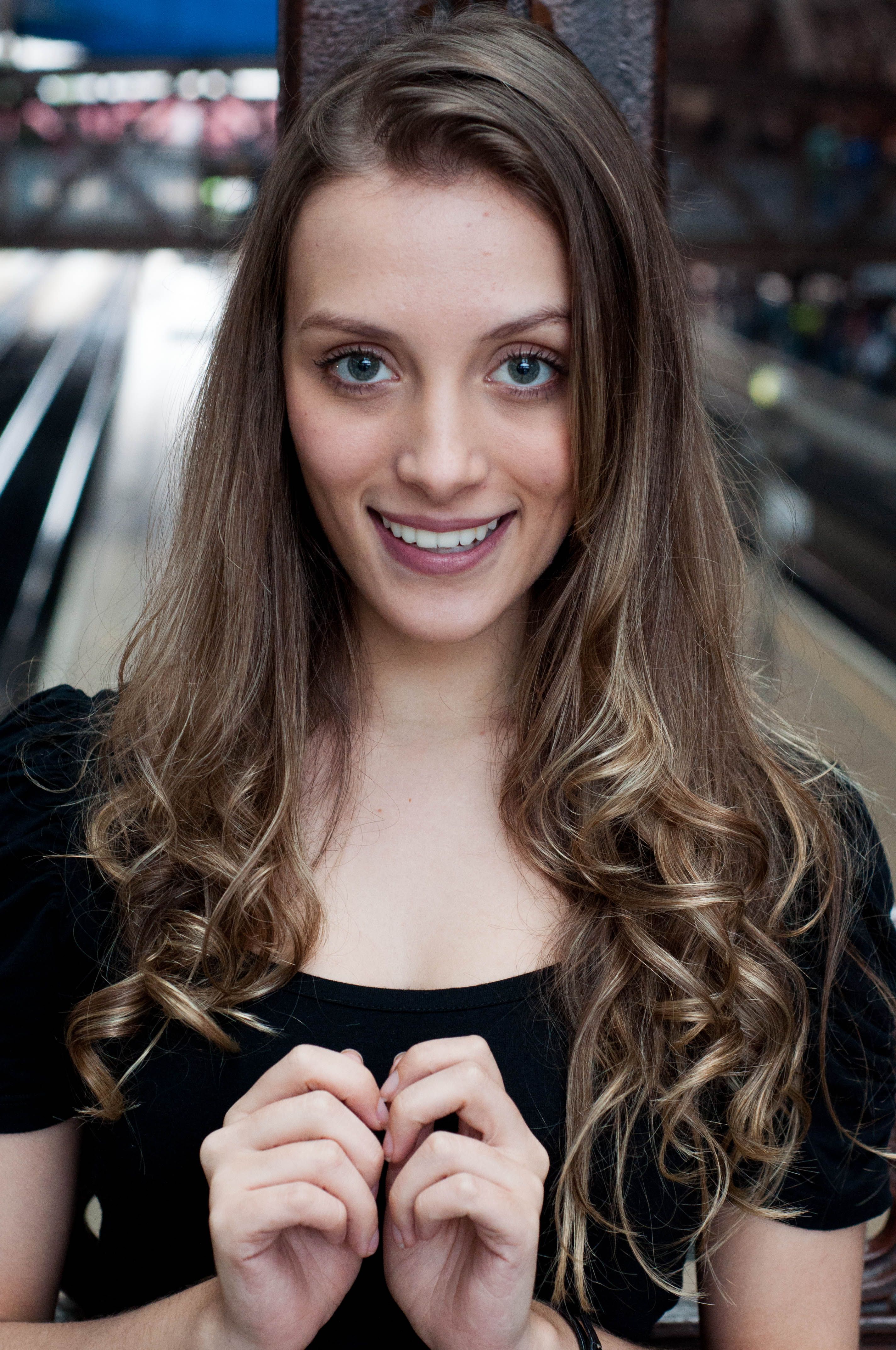 Charming portrait of a young woman with long curly hair smiling warmly.