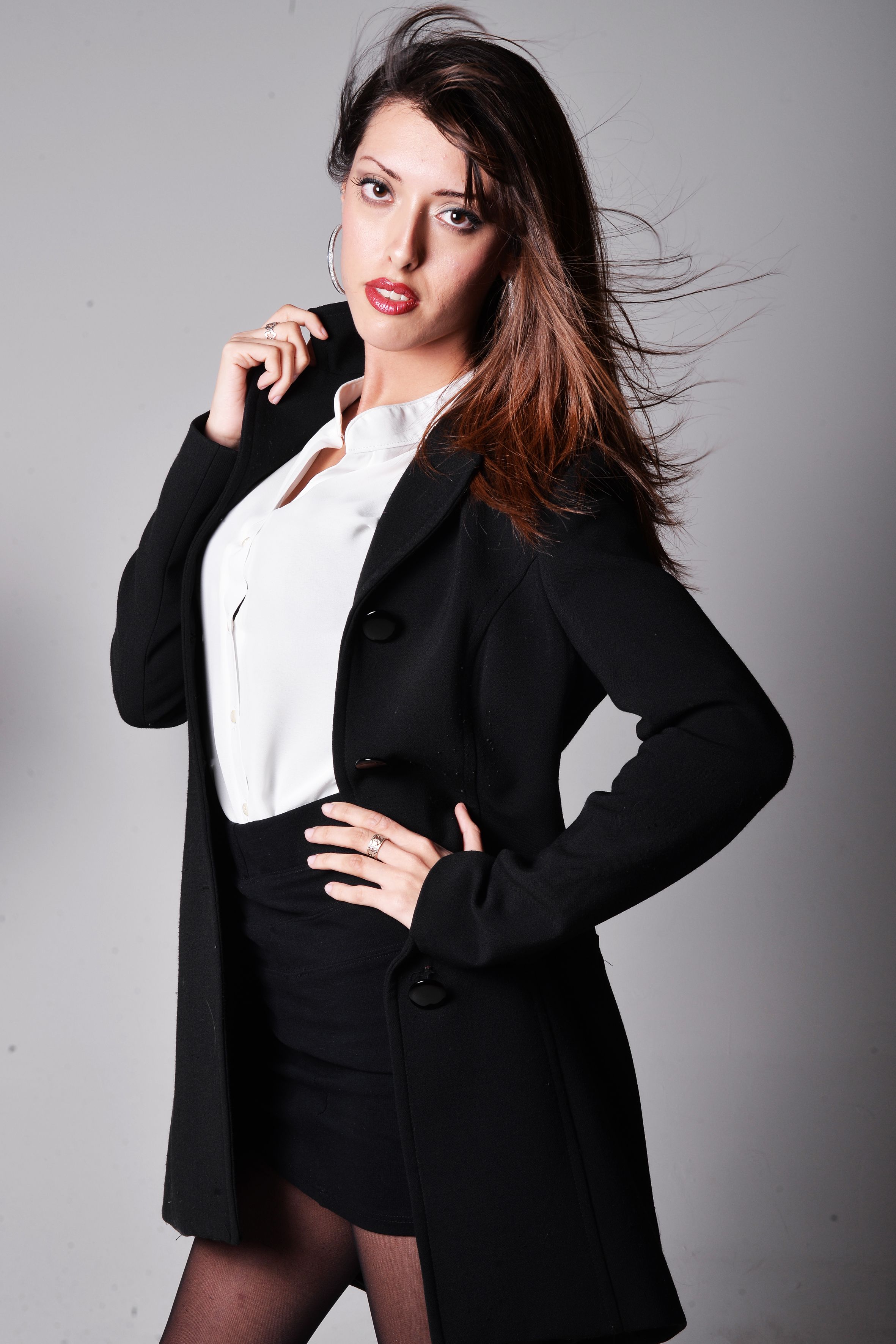 Portrait of a stylish young woman in a black coat and white blouse. Perfect for fashion and business themes.
